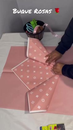 a person cutting fabric on top of a pink table cloth with scissors and other crafting supplies