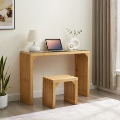 a wooden desk with a laptop on top of it next to a potted plant