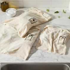 three towels are sitting on the counter next to a sink and soap dispenser