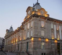 an old building with a clock on the top of it's tower at dusk