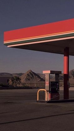 an empty gas station with mountains in the background and no one at the fuel pump