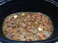 a crock pot filled with meat and onions in the slow cooker, ready to be cooked