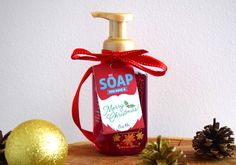 a bottle of soap sitting on top of a wooden table next to pine cones and christmas decorations