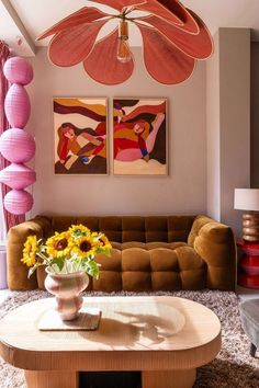 a living room filled with furniture and paintings on the wall next to a coffee table