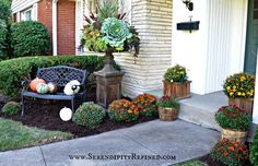 a bench sitting in front of a house with potted plants and pumpkins on the ground