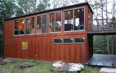 a small wooden house sitting on top of a lush green hillside next to a forest