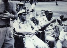 a group of men sitting next to each other on top of a grass covered field