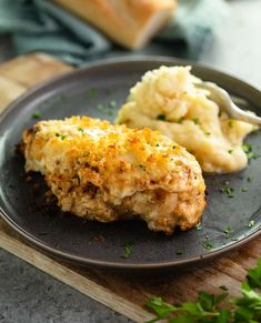 a black plate topped with chicken and mashed potatoes