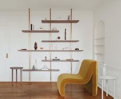 a yellow chair sitting in front of a shelf filled with bottles and vases on top of wooden shelves