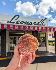 a person holding up a donut in front of a store