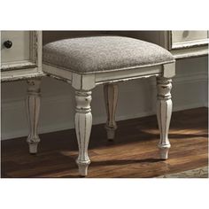 an antique white vanity with mirror and stool