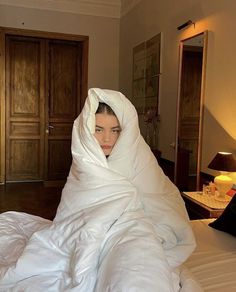 a woman wrapped in a blanket on top of a bed