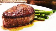 a steak and green beans on a white plate