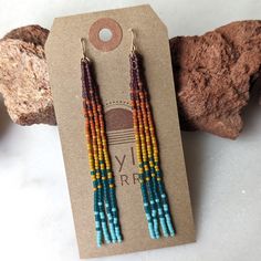 Embrace your inner bohemian goddess with our fan favorite long fringe beaded earrings. This unique rainbow color effect is inspired by a vibrant sunset over the ocean. Beautifully dramatic, comfortably lightweight. Enjoy the playful, free flowing style of beaded fringe earrings, without the weight. Featuring 4 strands of hand woven matte glass beads. These unique matte glass beads have a very luxe look and feel to them. Colors: These beaded earrings feature an ombre fade of semi-transparent purp Ombre Beaded Earrings, Sunset Rainbow, Fringe Beaded Earrings, Sunset Over The Ocean, Beaded Fringe Earrings, Long Fringe, Long Fringes, Rainbow Beads, Gold Alloys