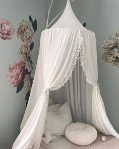 a white canopy bed with flowers on the wall