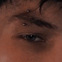 a man with piercings on his nose looking at the camera