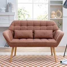 a brown couch sitting on top of a checkered floor in front of a window