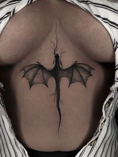 a woman's back with a dragon tattoo on her lower back and the upper part of her stomach