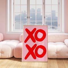 a red xo sign sitting on top of a wooden floor next to a white couch