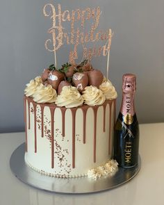 a birthday cake with chocolate and strawberries on top, next to a bottle of champagne