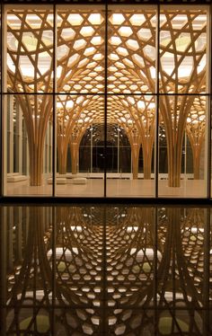 the inside of a building with large windows and wood carvings on the walls, reflecting water