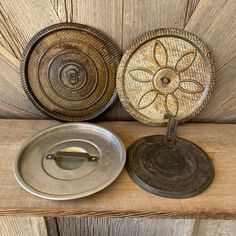 two metal plates sitting next to each other on a wooden table with an iron lid