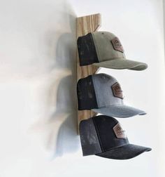 three hats are hanging on the wall in front of a hat rack with two baseball caps