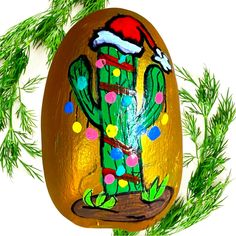 an easter egg decorated with christmas decorations and a cactus painted on the side, surrounded by pine branches