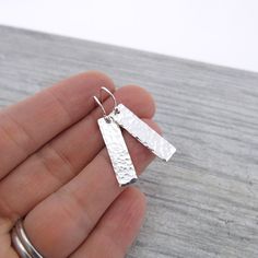 A modern twist on a classic pair of 1 inch vertical bar drop earrings. Simple, rustic, lightweight and utterly perfect for everyday wear for yourself or to give as a treasured gift.  Dainty and delicate sized 1 inch Sterling Silver rectangle bars hammered and textured with my modern Classic texture, then simply suspended from Sterling Silver balled earwires. The bars are tumble polished for shine. The total length of the earrings from the top of the earwires to the bottom of the rectangles is 1 Minimalist Hammered Rectangular Earrings, Everyday Modern Rectangular Linear Earrings, Earrings Handmade Silver, Silver Bar Earrings, Handmade Silver Jewelry, Hammered Earrings, Rectangle Earrings, Silver Earrings Handmade, Silver Bar