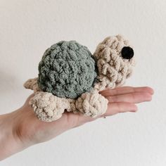 a hand holding a small crocheted turtle