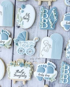 baby shower cookies decorated with blue and white icing on a wooden table next to cookie cutters