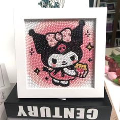 a cross stitch picture in a white frame on top of a black and white box