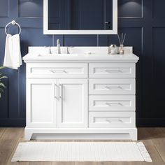 a white bathroom vanity with blue walls and wooden flooring in front of a large mirror