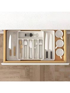 a drawer with utensils and spoons in it on top of a wooden floor