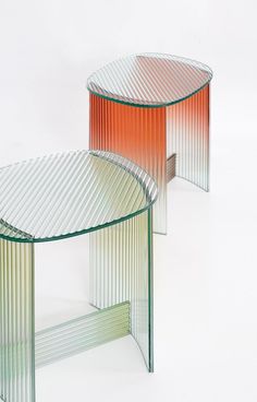 two glass tables sitting next to each other on top of a white surface with red and green stripes