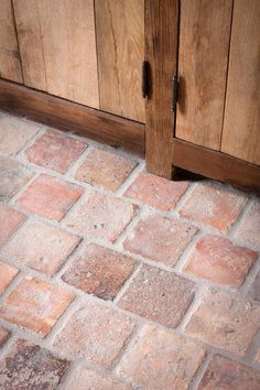 a close up of a brick floor with wooden cabinets in the backgroung