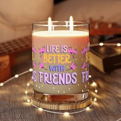 a lit candle with the words life is better with friends on it sitting on a table