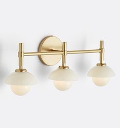 three light brass bathroom fixture with white glass globes on the sides and gold metal arms