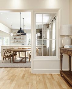 an open kitchen and dining room with wood flooring, white walls and wooden furniture