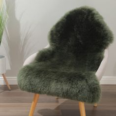 a green chair sitting on top of a hard wood floor next to a potted plant