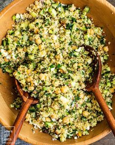 a wooden bowl filled with broccoli and other food on top of a table