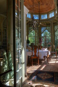 the sun shines through an arched glass door into a dining room with tables and chairs