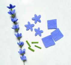 blue flowers and felt pieces laid out on a white surface