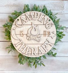 a wooden sign with the words camping is my therapy on it and an image of a campfire