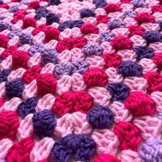 a crocheted blanket with pink, purple and red colors