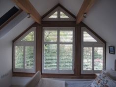 an attic bedroom with wooden shutters on the windows and a bed in the corner