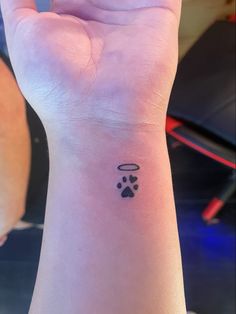 a small wrist tattoo with an angel and paw prints on the left side of the wrist