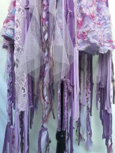 two purple scarves are hanging on a white wall and one is covered in lace