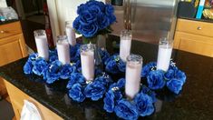 blue flowers and candles are arranged on a kitchen counter