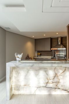 a kitchen with marble counter tops and an island in the middle is seen from across the room